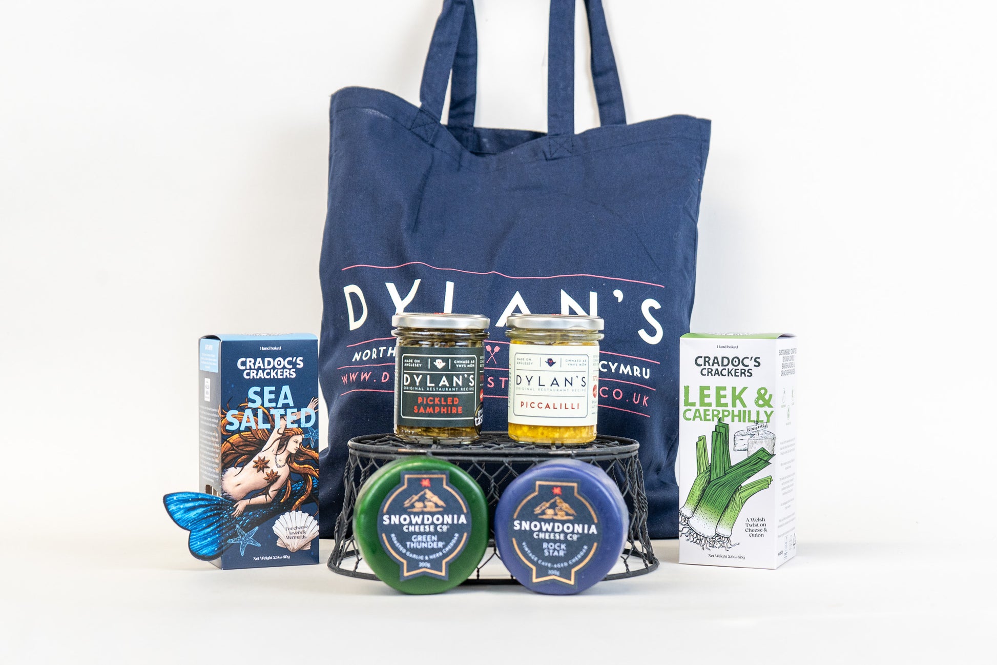 Dylan's products including a tote bag, welsh cheese, welsh crackers, piccalilli and pickled samphire on a white background