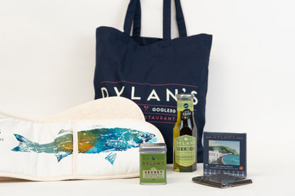 Navy tote bag with 'Dylan's' branding, a white tote bag with fish design, and various items on a white background.