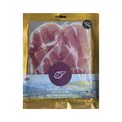 Packaged air-dried cured Welsh ham with gold and purple packaging on a white background
