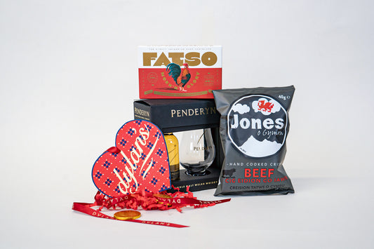 Assorted food products including a bag of Jones beef chips, a bottle of Penderyn whisky, and a box of Fatso chocolates on a white background.